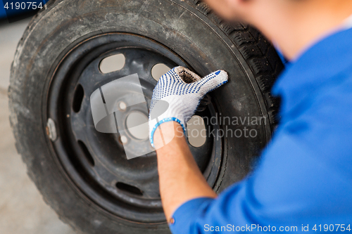 Image of mechanic with wheel tire at car workshop