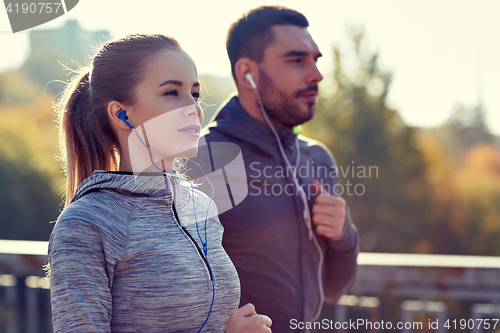 Image of happy couple with earphones running in city