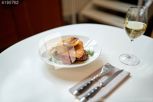 Image of fish salad and wine glass on restaurant table 