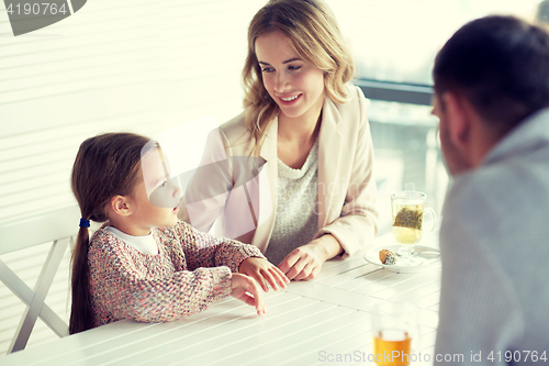 Image of happy family having dinner at restaurant or cafe