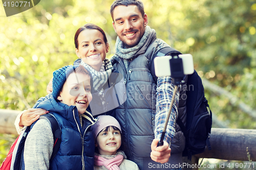 Image of happy family with smartphone selfie stick in woods