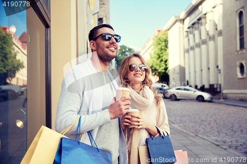 Image of happy couple with shopping bags and coffee in city