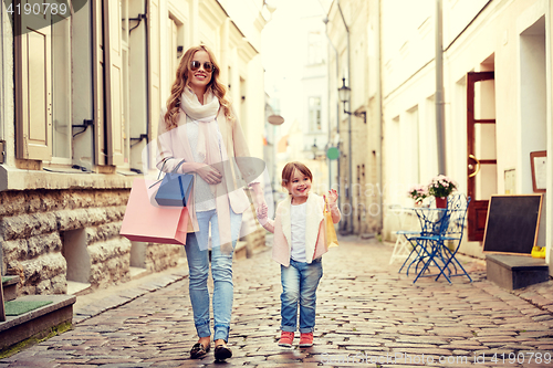 Image of happy mother and child with shopping bags in city