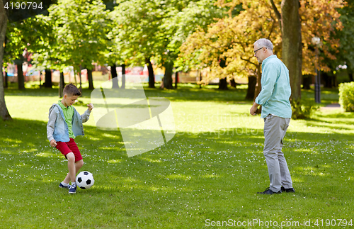 Image of old man and boy playing football at summer park