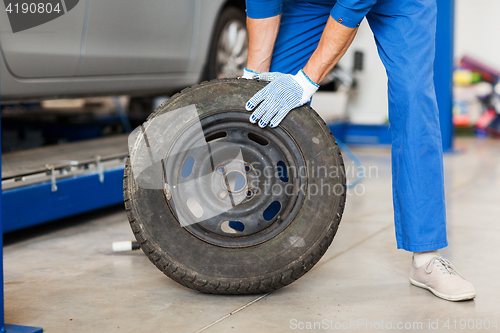 Image of mechanic with wheel tire at car workshop