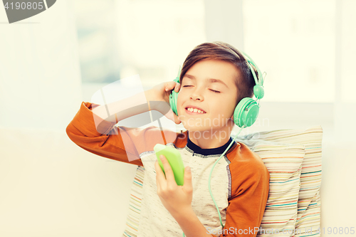 Image of happy boy with smartphone and headphones at home