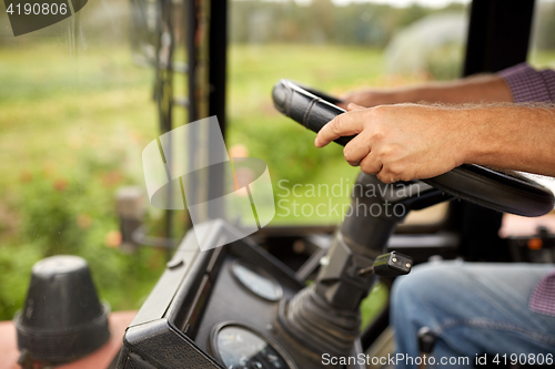 Image of senior man driving tractor at farm