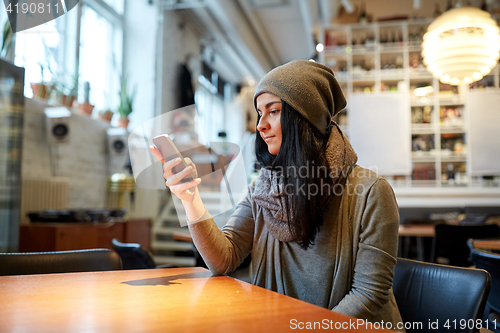 Image of young woman with smartphone at cafe