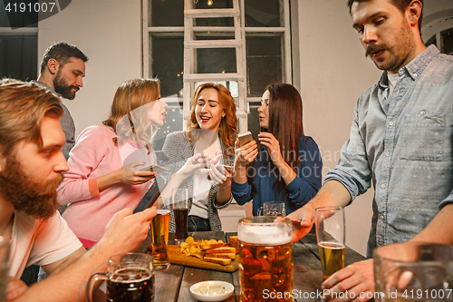 Image of Group of friends enjoying evening drinks with beer