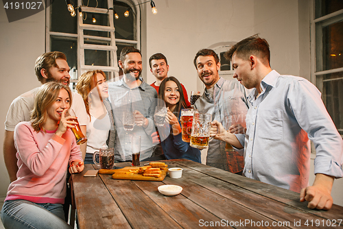 Image of Group of friends enjoying evening drinks with beer