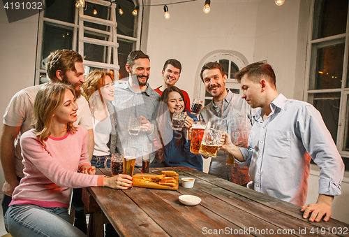 Image of Group of friends enjoying evening drinks with beer