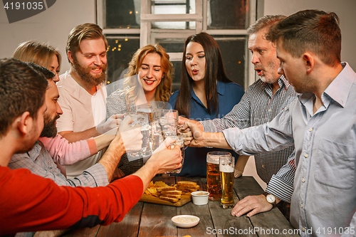 Image of Group of friends enjoying evening drinks with beer