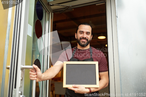 Image of man or waiter with blackboard at bar entrance door