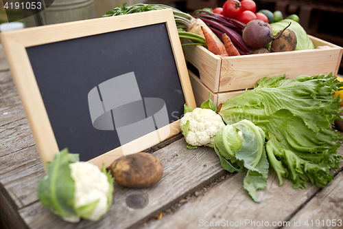 Image of close up of vegetables with chalkboard on farm