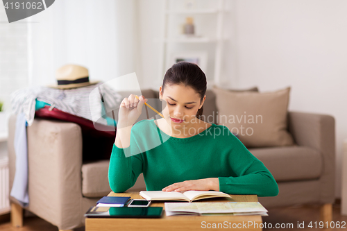 Image of woman with notebook and travel map at home