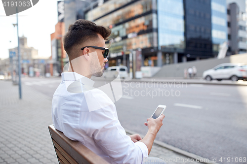 Image of close up of man texting on smartphone in city