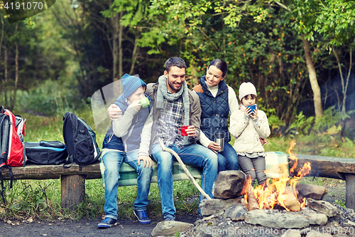 Image of happy family sitting on bench at camp fire