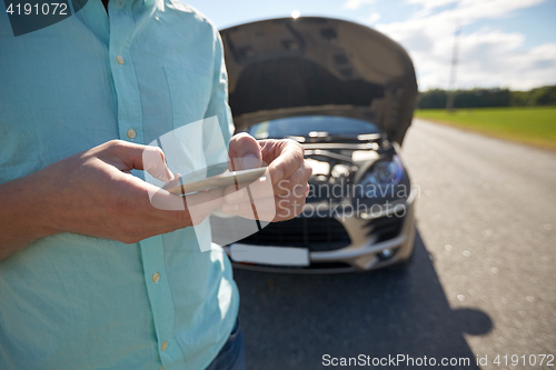 Image of close up of man with smartphone and broken car