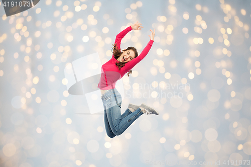 Image of happy young woman jumping or dancing over lights