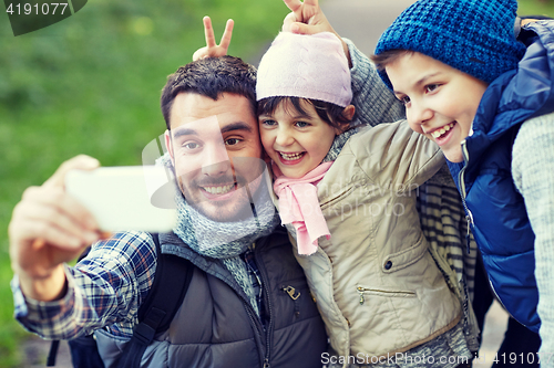 Image of family taking selfie with smartphone outdoors