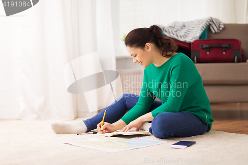 Image of woman with notebook and travel map at home