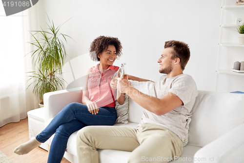 Image of happy friends or couple with beer talking at home