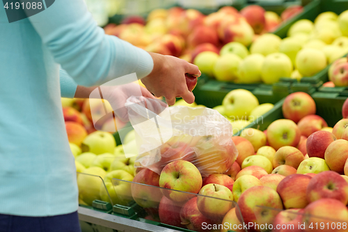 Image of woman with bag buying apples at grocery store