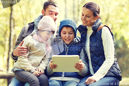 Image of family sitting on bench with tablet pc at camp