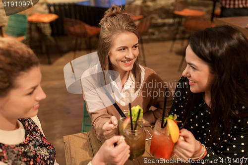 Image of happy friends clinking drinks at restaurant