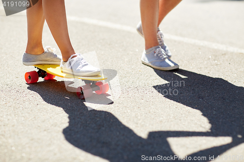 Image of feet of teenage couple riding skateboard on road