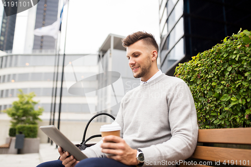 Image of man with tablet pc and coffee on city street bench