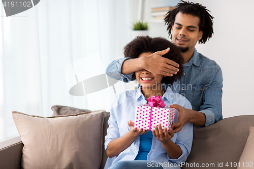 Image of happy couple with gift box at home