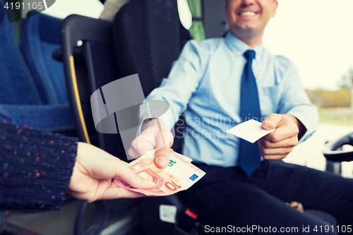 Image of close up of bus driver selling ticket to passenger