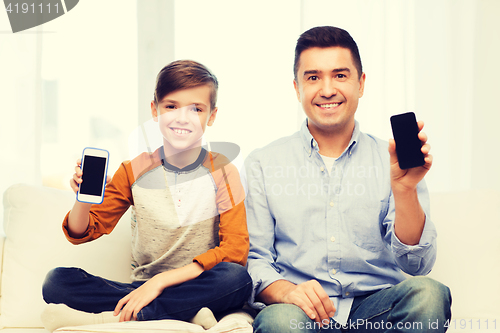 Image of happy father and son with smartphones at home