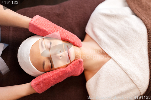 Image of woman having face massage with terry gloves at spa