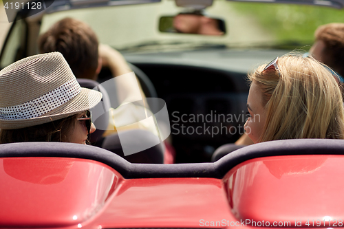 Image of happy friends driving in convertible car at summer