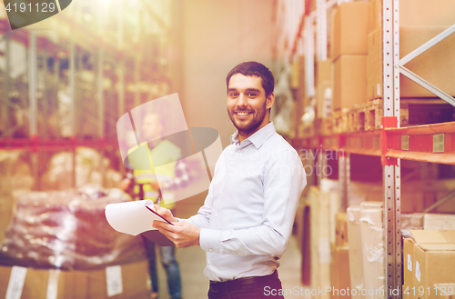 Image of happy businessman with clipboard at warehouse