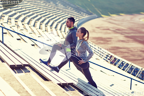 Image of couple stretching leg on stands of stadium