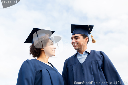 Image of happy students or bachelors in mortarboards