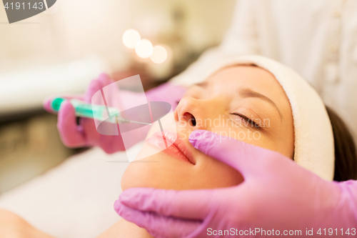 Image of beautician doing beauty injection to woman lips