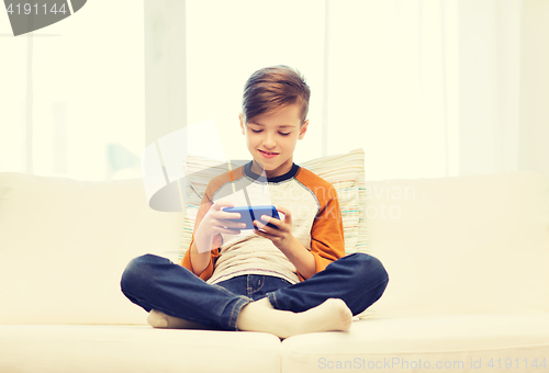 Image of boy with smartphone texting or playing at home