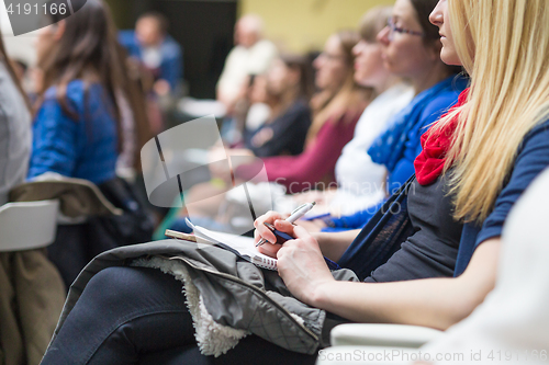 Image of Hands holding pens and making notes at conference lecture.