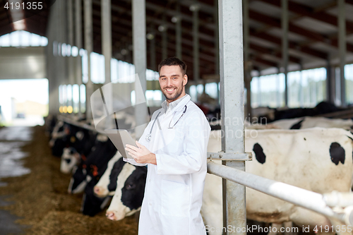 Image of veterinarian with tablet pc and cows on dairy farm