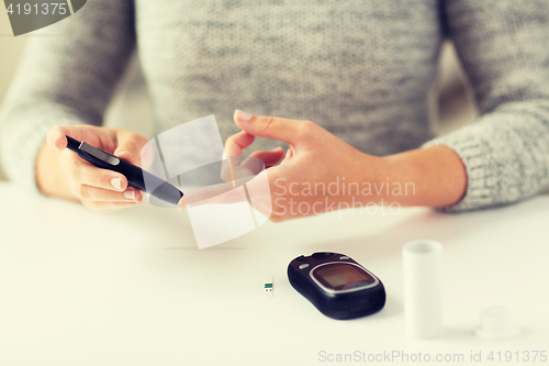 Image of close up of woman making blood test by glucometer