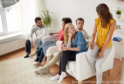 Image of happy friends with popcorn and beer at home