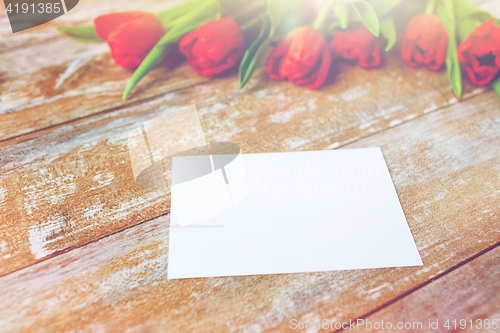 Image of close up of red tulips and blank paper or letter