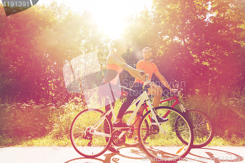 Image of happy couple riding bicycle outdoors