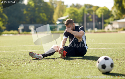 Image of injured soccer player with ball on football field