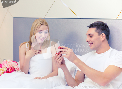 Image of man giving woman little red box and ring in it