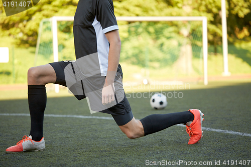 Image of soccer player stretching leg on field football